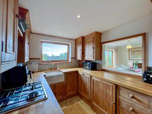 a kitchen with wooden cabinets and a sink and a stove at Drovers Cottage in Tetbury