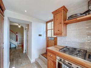 a kitchen with wooden cabinets and a stove top oven at Drovers Cottage in Tetbury +14 photos