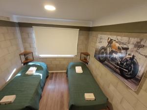 a room with two beds and a picture of a motorcycle on the wall at Cyclotel Motoposada in Valle Hermoso
