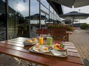 a tray of eggs and bread on a table with juice at Ibis Vienna Airport in Schwechat