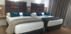 two beds in a hotel room with blue pillows at Hoteles Casa Aika in Lima +3 photos