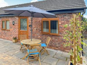 a table and chairs with an umbrella on a patio at The Old Milking Parlour in Melverley