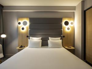 a bedroom with a large white bed with two pillows at Novotel Brussels Centre Midi in Brussels