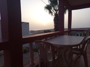una mesa y sillas en un balcón con vistas a la puesta de sol en tasurft house imsoune, en Imsouane
