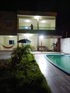 osoba stojąca na balkonie obok basenu w nocy w obiekcie Sonho de Verão - Casa de Praia, Pitimbu PB - 50 Metros do mar - QUASE PÉ NA AREIA w mieście Pitimbu