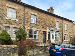 a blue car parked in front of a brick house at Hollybush Cottage in Buxton