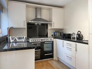 a kitchen with white cabinets and a stove top oven at Hollybush Cottage in Buxton +9 photos