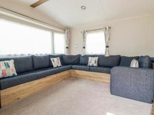 a living room with a blue couch and two windows at 82 Hillside in Newquay
