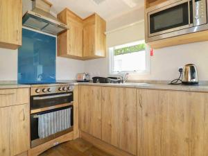 a kitchen with wooden cabinets and a sink and a stove at 82 Hillside in Newquay