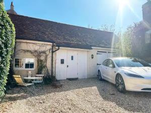 a white car parked in front of a garage at Boutique Cottage in the Heart of Kintbury in Kintbury