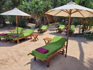 un groupe de chaises et de parasols sur une plage dans l'établissement Spirit of Life Ayurveda and Yoga Resort, à Induruwa