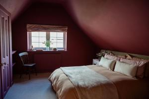 a red bedroom with a bed and a window at Boutique Cottage in the Heart of Kintbury in Kintbury