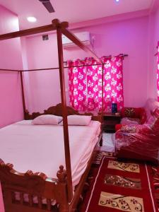 une chambre avec un lit à baldaquin et un éclairage rose dans l'établissement Hotel ruposhi bangla, à Purbbadulki