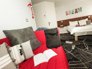 a red couch with books on it in a bedroom at ibis Styles Chartres Métropole in Chartres