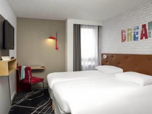 a hotel room with a bed and a red chair at ibis Styles Chartres Métropole in Chartres