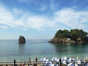 a group of people standing on a beach near an island at Parginaki House in Parga