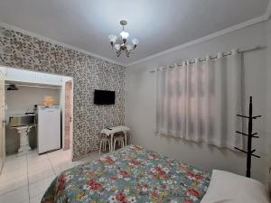 a bedroom with a bed and a television and a refrigerator at Loft in the Center of Serra Negra in Serra Negra