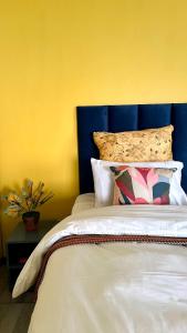a bed with a blue headboard and a yellow wall at Velvet Oasis Mbabane in Mbabane