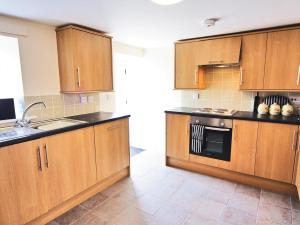 a kitchen with wooden cabinets and a sink at Little Barn - Hw7615 in Bettws-yn-Rhôs