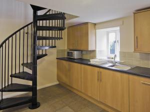 a kitchen with a spiral staircase next to a sink at Little Barn - Hw7615 in Bettws-yn-Rhôs