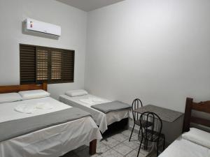 a room with two beds and a table and chairs at HOTEL TROPICAL in Jardim