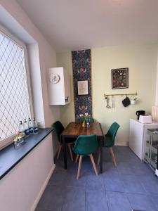 ブレーマーハーフェンにあるZentrales Apartment Yachthafen free parkingのテーブルと緑の椅子とテーブルのあるキッチン