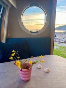 a vase of flowers sitting on a table with a window at Enkel, romslig og kul campingvogn in Moskenes +2 photos