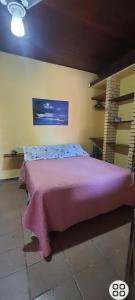 um quarto com uma cama rosa e um cobertor rosa em Chales praias de Ubatuba em Ubatuba