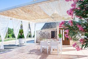 un patio avec une table et des chaises sous une pergola dans l'établissement I Tre Trulli, à Locorotondo
