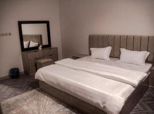 a bedroom with a large white bed with a mirror at Sukoon Buraydah سكون بريدة in Buraydah