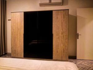 a large wooden cabinet with a glass door in a bedroom at Sukoon Buraydah سكون بريدة in Buraydah