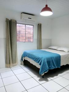 a bedroom with a bed with a blue blanket on it at Furtado Temporada in Santo Amaro