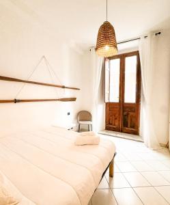 Un dormitorio blanco con una cama y una silla. en Kalma - Azuni Piazza Jenne, en Cagliari