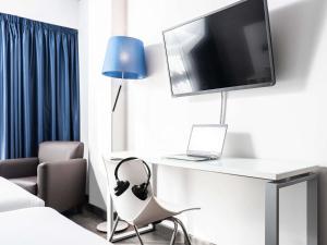 a room with a desk with a laptop and a tv at Ibis Styles A Coruna in A Coruña