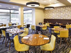 a restaurant with wooden tables and yellow chairs at Mercure Sheffield Parkway in Sheffield