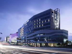 a tall glass building with a street in front of it at Novotel Ambassador Suwon in Suwon