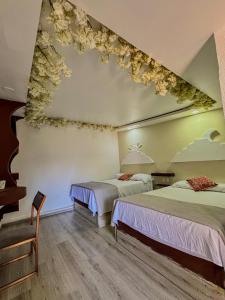two beds in a room with flowers on the ceiling at Vicalis Hotel, Villas y Glamping in San Sebastian Xolalpa