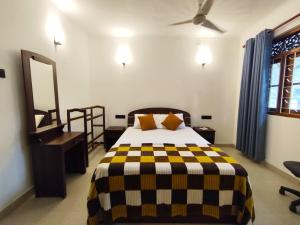 - une chambre avec un lit doté d'une couverture noire et jaune dans l'établissement Priyanwada Lake Cottage, à Nikawatawana