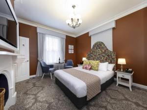 a hotel room with a bed and a television at Grand Mercure Basildene Manor in Margaret River Town +46 photos