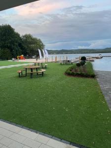 a group of picnic tables on the grass near the water at Apartament Przystań Nadole in Nadole