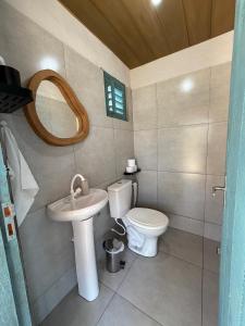a bathroom with a toilet and a sink and a mirror at Céu - Quarto com entrada privada in Luis Correia