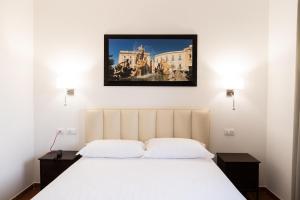 a bedroom with a white bed and a painting on the wall at Tenuta Madre Vita in Syracuse