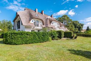 een groot huis met een rieten dak bij Born - Wieck Ferienwohnung Wildrose in Wieck