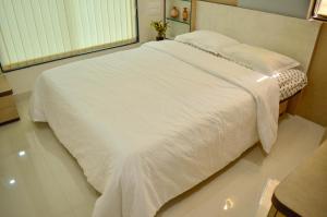 ein Schlafzimmer mit einem Bett mit weißen Laken und einem Fenster in der Unterkunft Rk Stay 2bhk Balewadi Highstreet Fully Furnished Premium in Pune