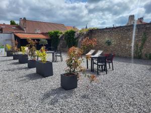a row of tables and chairs and potted plants at Aparthotel Des 2 Caps in Ambleteuse