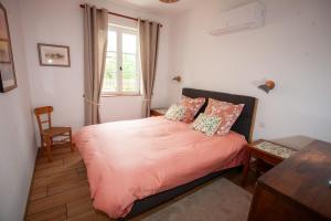 a bedroom with a bed with pink sheets and a window at Gite Passart à Brancion in La Chapelle-sous-Brancion