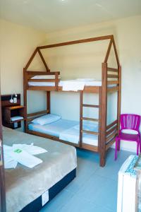 two bunk beds in a room with a pink chair at Pousada Paraíso Tropical in Penha