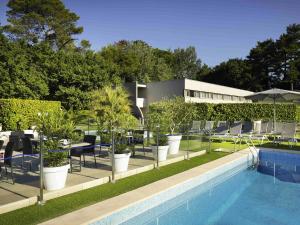 a swimming pool with chairs and plants next to a building at Mercure Orange Centre A7/A9 in Orange