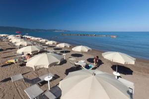 a bunch of white umbrellas on a beach at Happy Sea Home - monolocale sul mare in Albinia