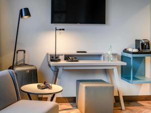 a room with a desk and a table with a tv at Mercure Hotel Dortmund Centrum in Dortmund